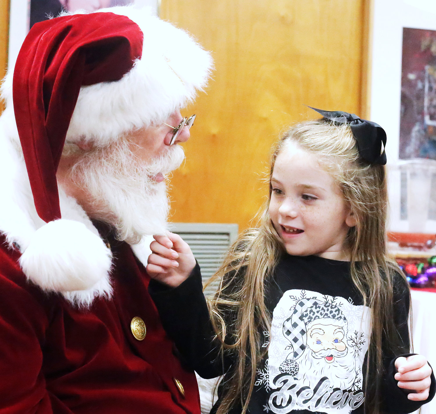 Madelynn Smith of Mineola gives Santa’s beard a little tug just to be sure he is real during a recent visit.